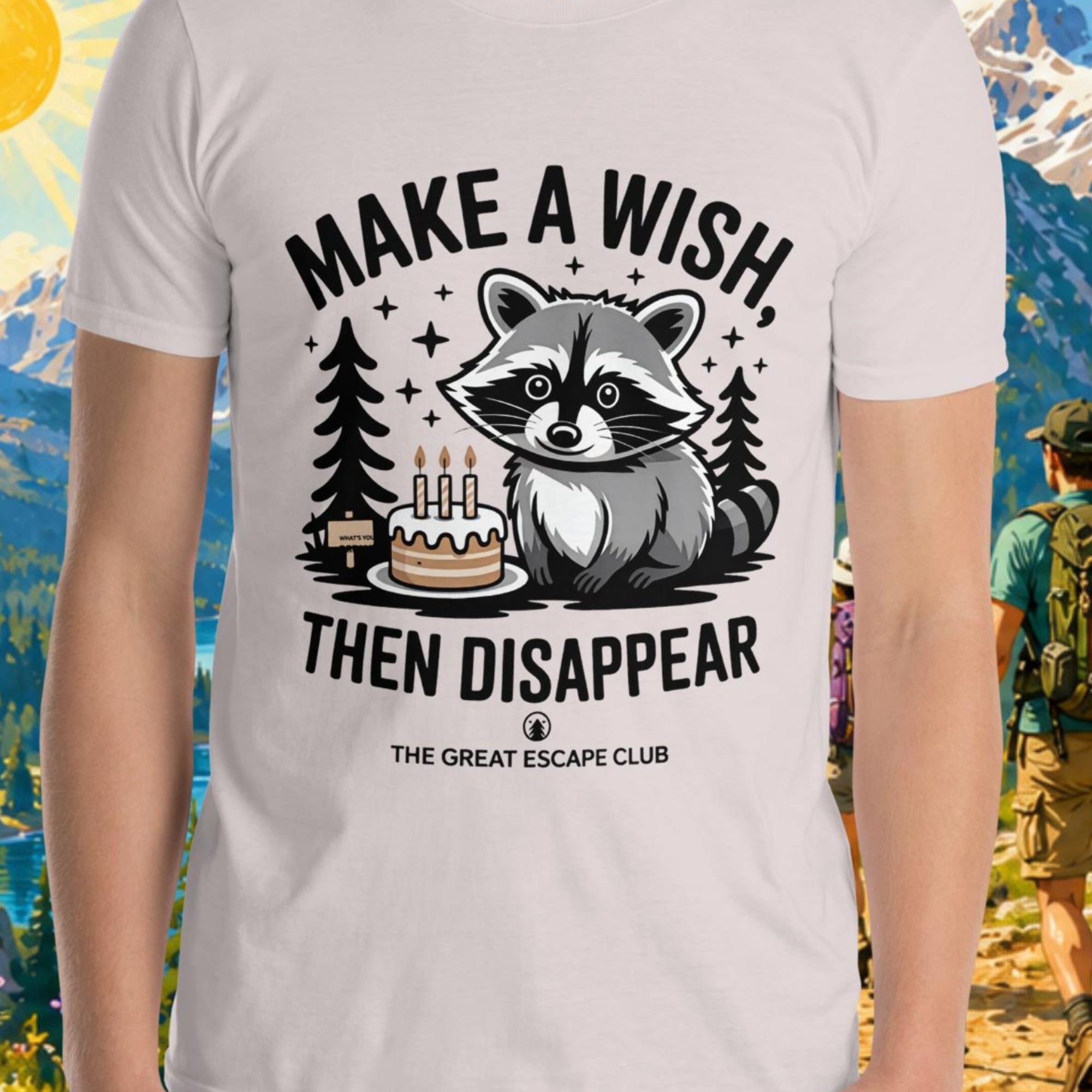 Person wearing a t-shirt with a raccoon graphic and text in a mountainous landscape