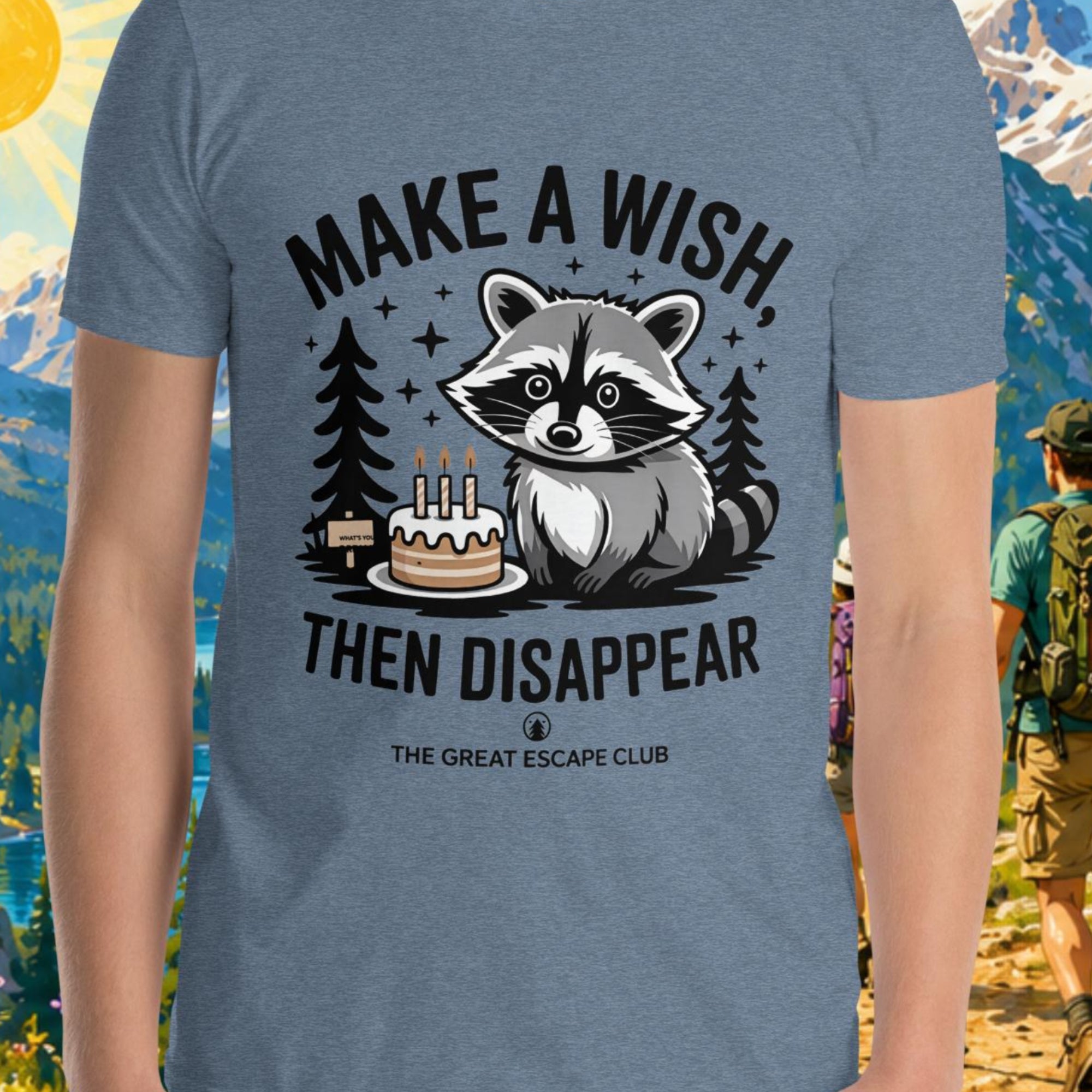 Person wearing a t-shirt with a raccoon graphic and text in front of a scenic mountain backdrop