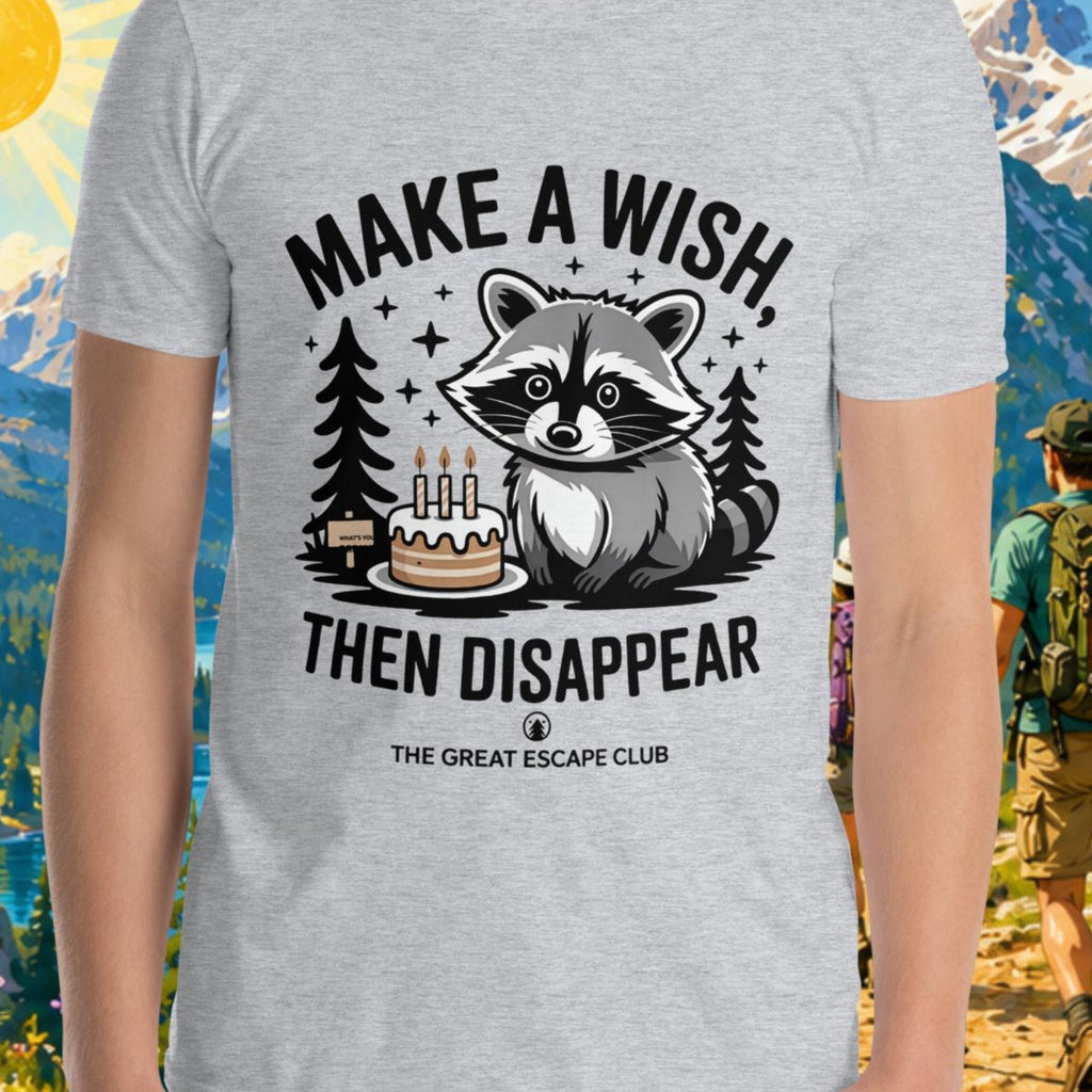 Person wearing a t-shirt with a raccoon graphic and text in a mountainous landscape