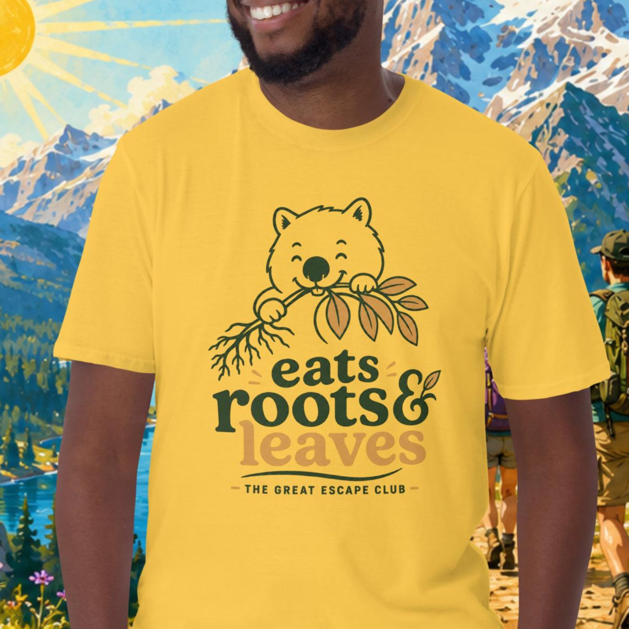 Man wearing a yellow t-shirt with a bear graphic and text, standing in front of a scenic mountain landscape.