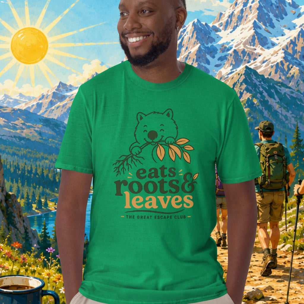 Man wearing a green t-shirt with 'eats roots & leaves' design, standing in front of a scenic mountain landscape.