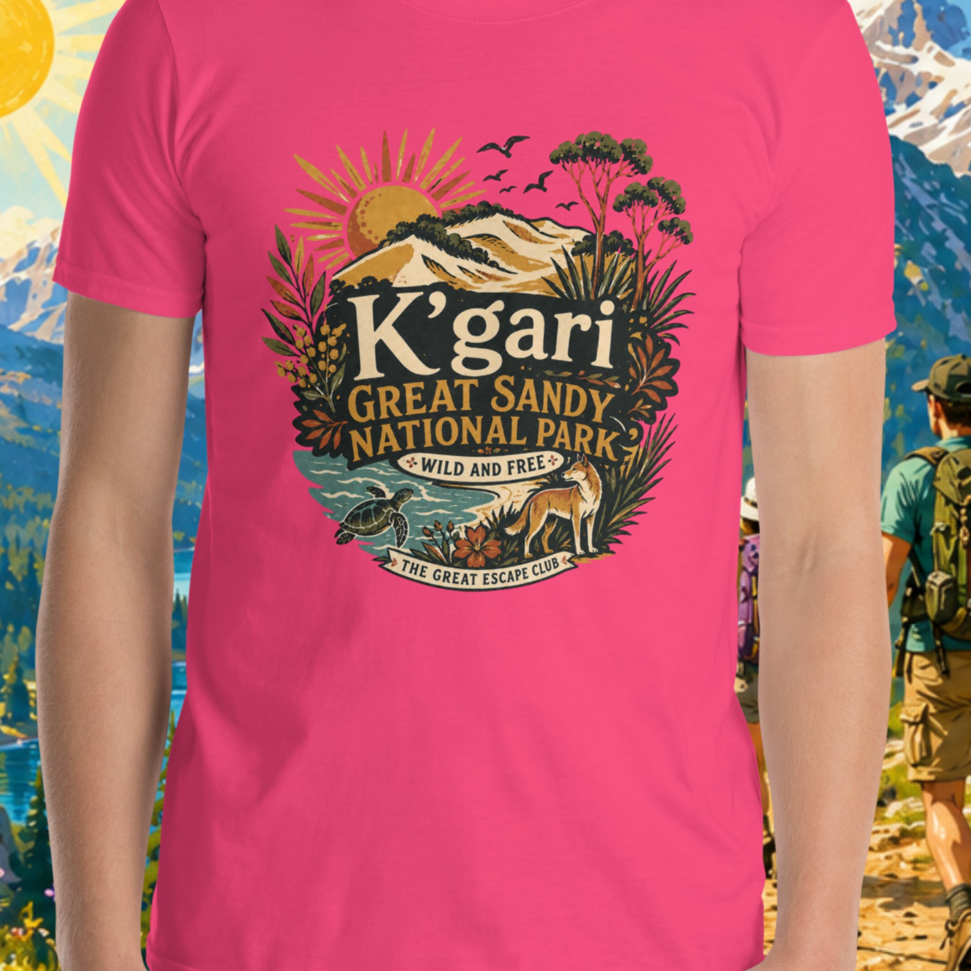 Person wearing a pink t-shirt with K'gari Great Sandy National Park design against a scenic mountain backdrop.