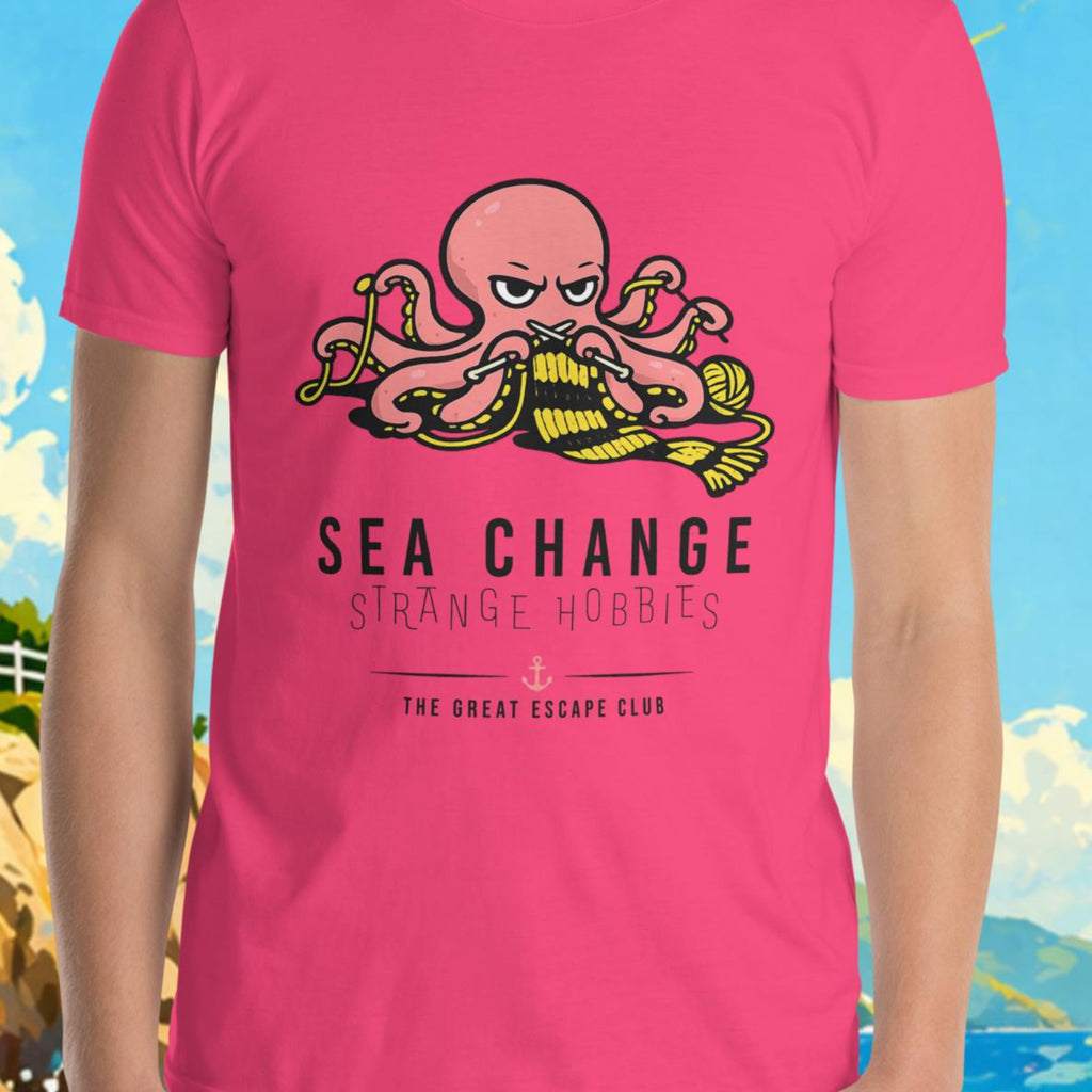 Person wearing a pink t-shirt with a graphic design in front of a scenic background with a lighthouse and sailboat.