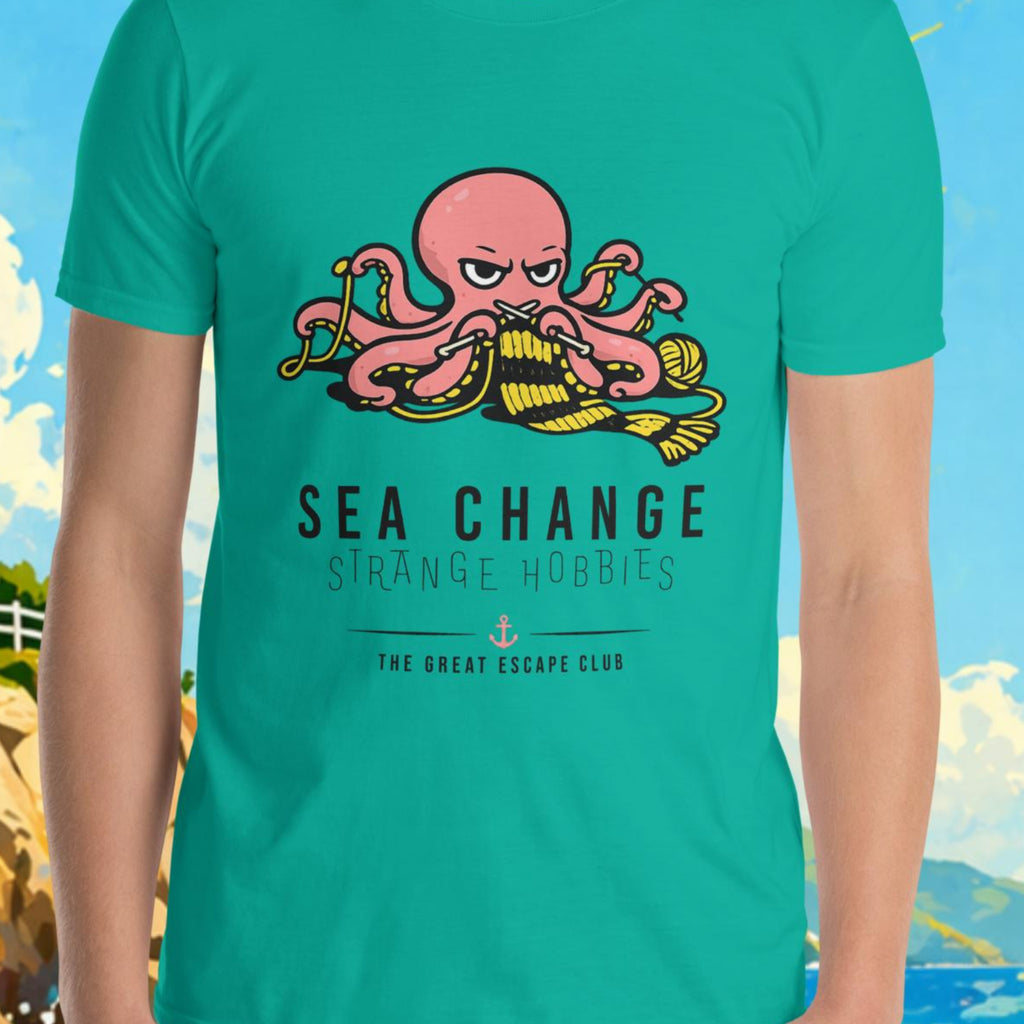 Person wearing a teal t-shirt with a graphic design in front of a scenic background with a lighthouse and sailboat.
