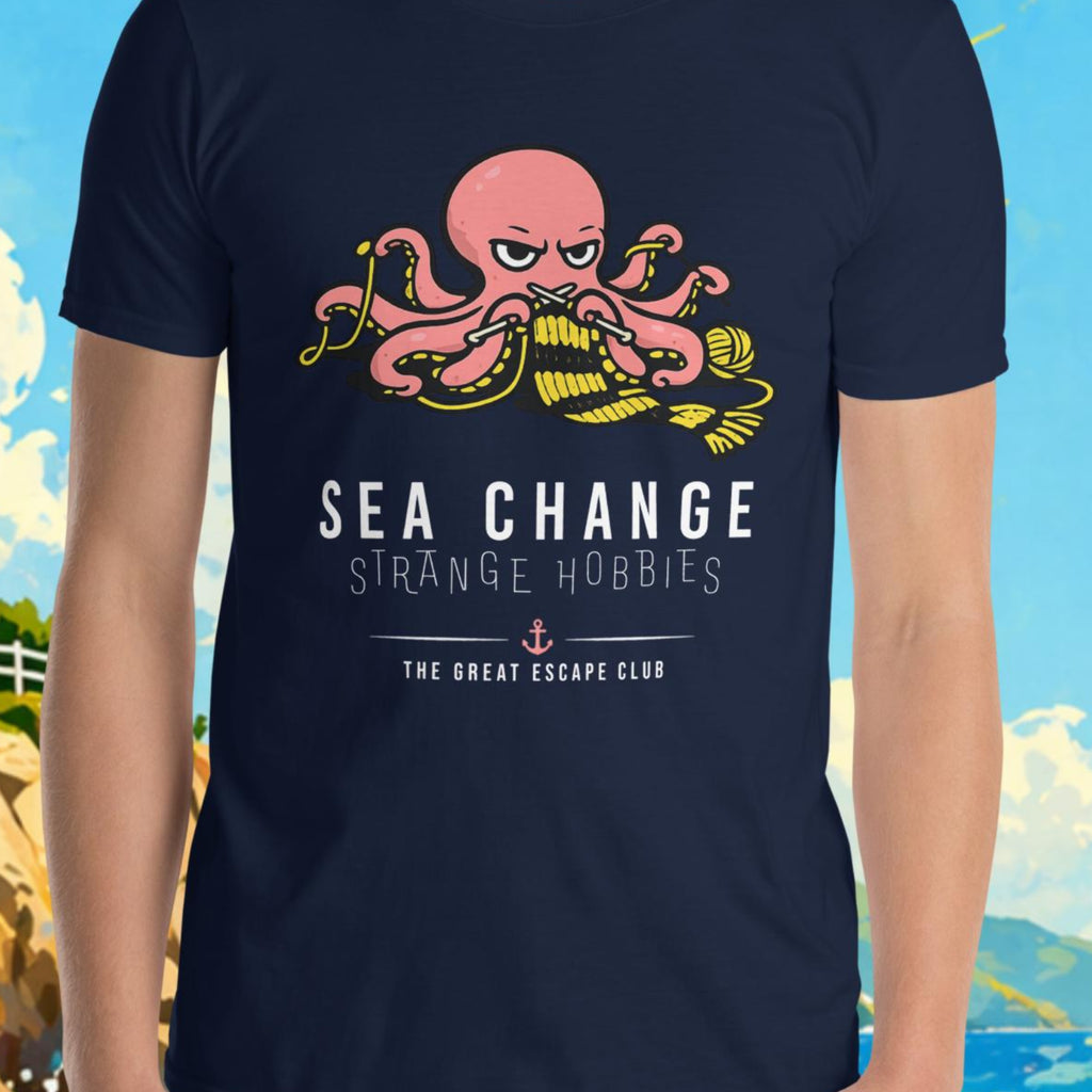 Person wearing a navy blue t-shirt with an octopus design and text, standing in front of a scenic background with a lighthouse and sailboat.