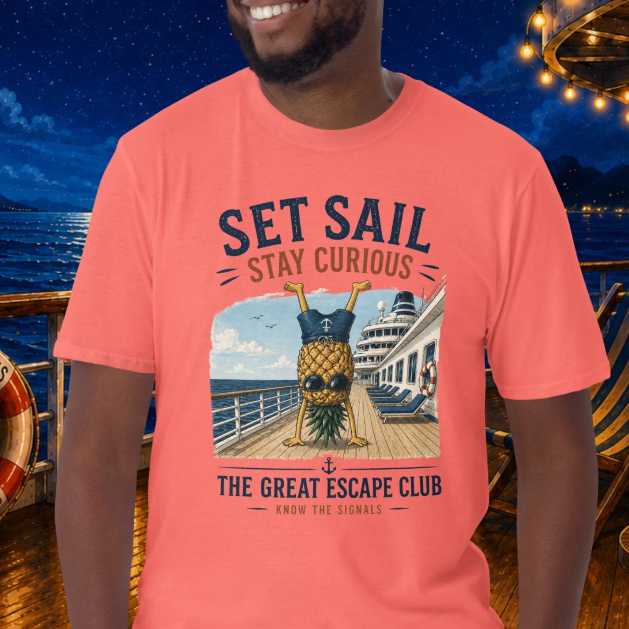 Man wearing a pink t-shirt with a pineapple graphic and text on a cruise ship deck at night.