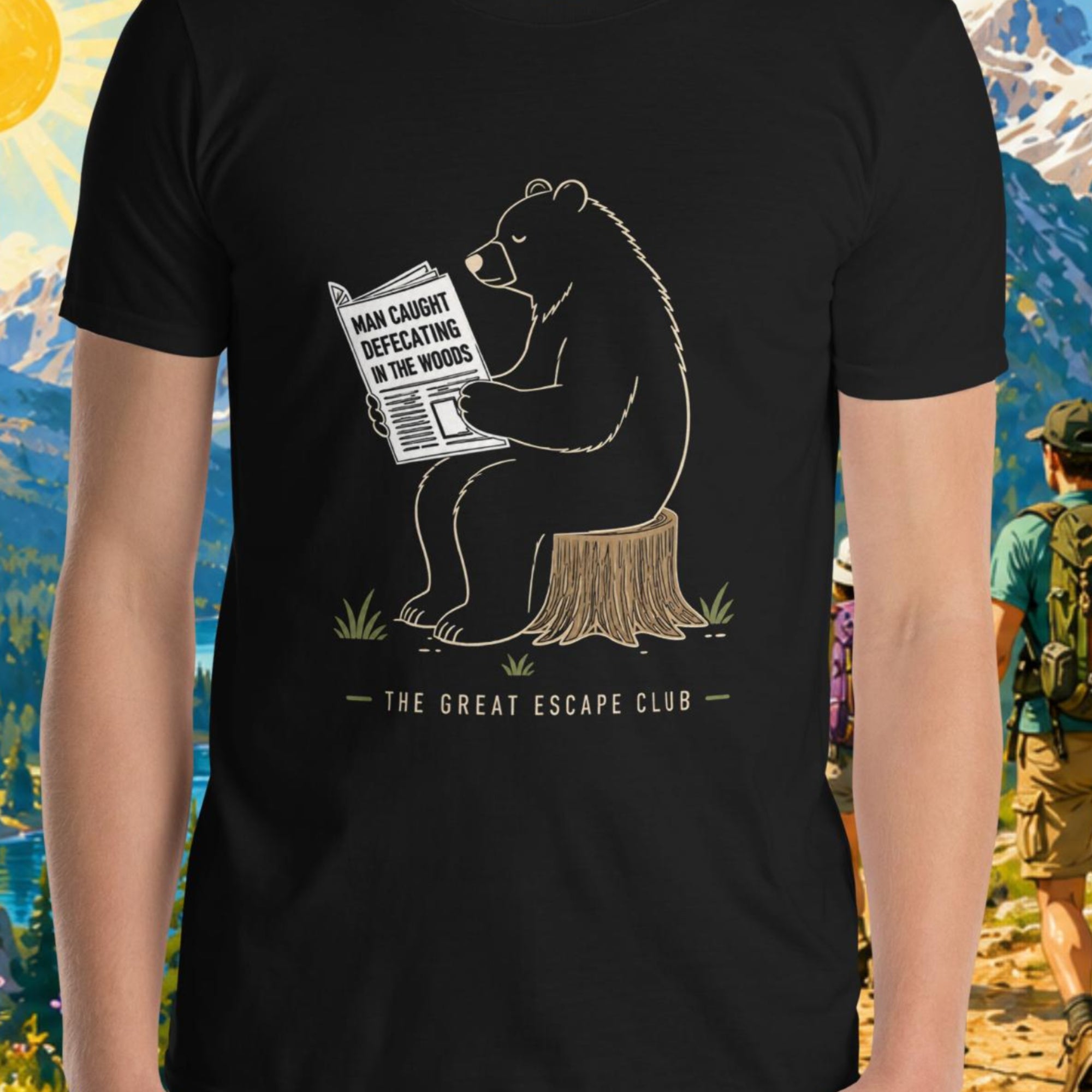 Person wearing a t-shirt with a bear graphic and text, standing in front of a scenic mountain backdrop.