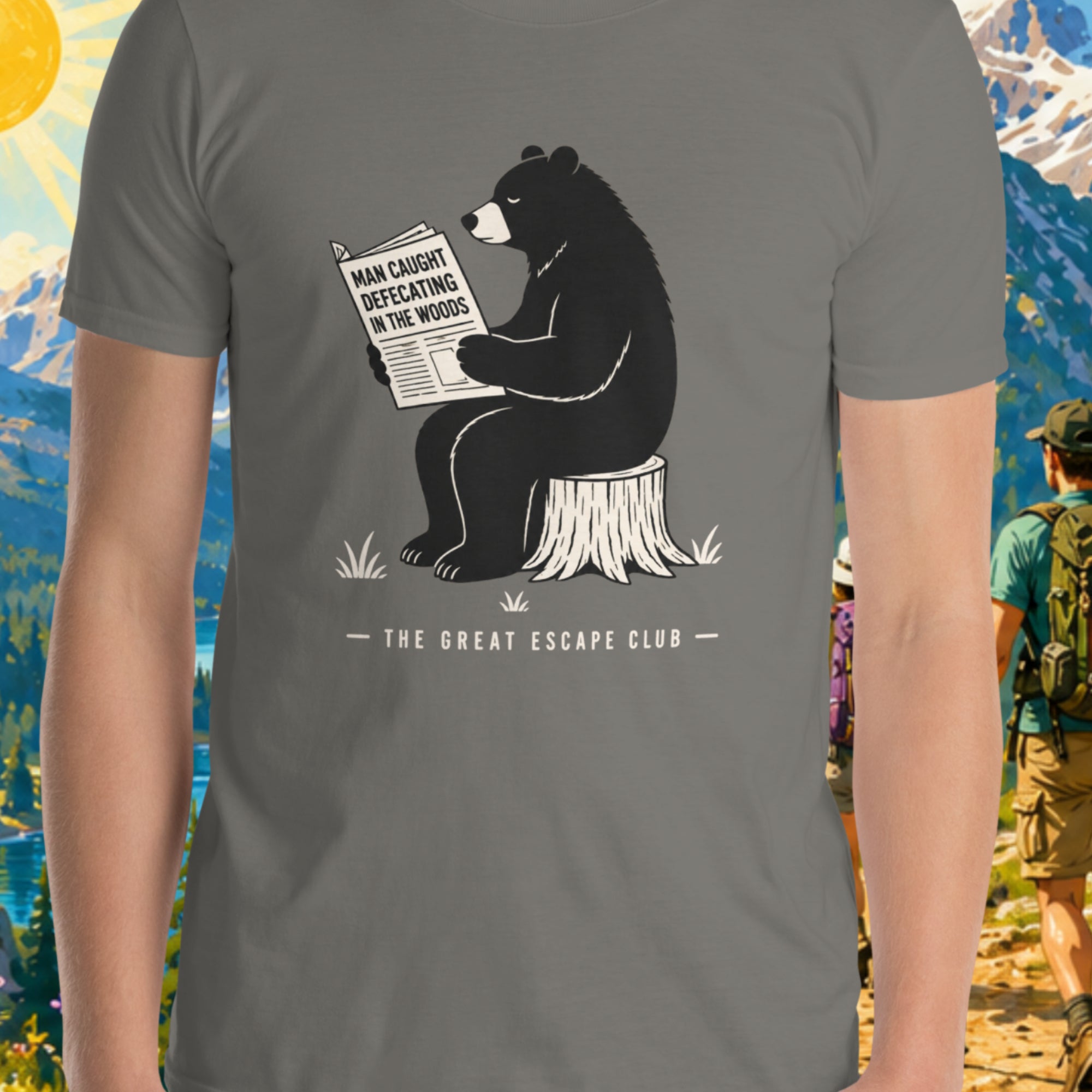 Gray t-shirt with a bear graphic reading a newspaper, 'The Great Escape Club' text, against a nature-themed background.