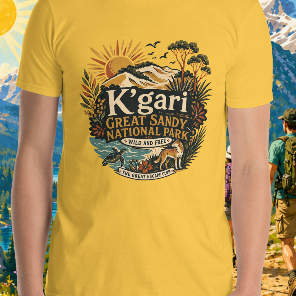 Person wearing a yellow t-shirt with 'K'gari Great Sandy National Park' design against a scenic mountain backdrop.