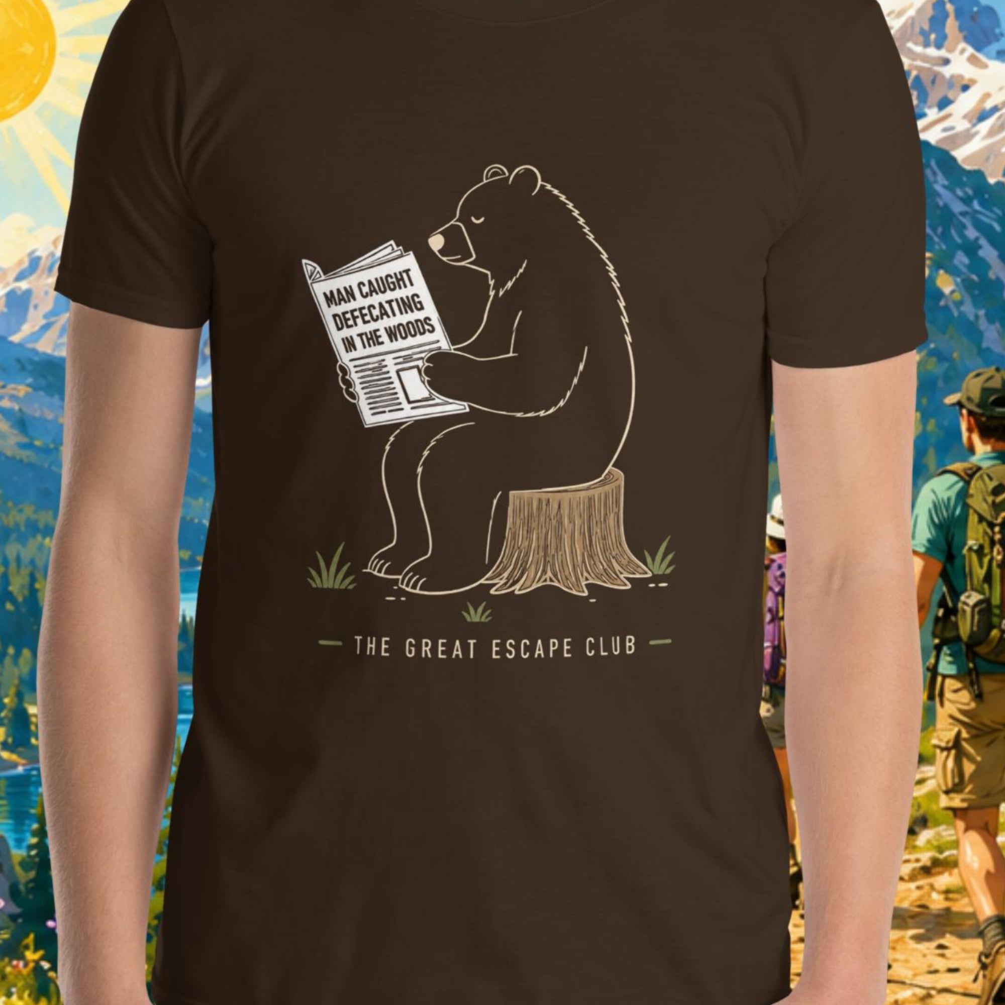 Person wearing a t-shirt with a bear graphic and text, standing in front of a scenic mountain backdrop.