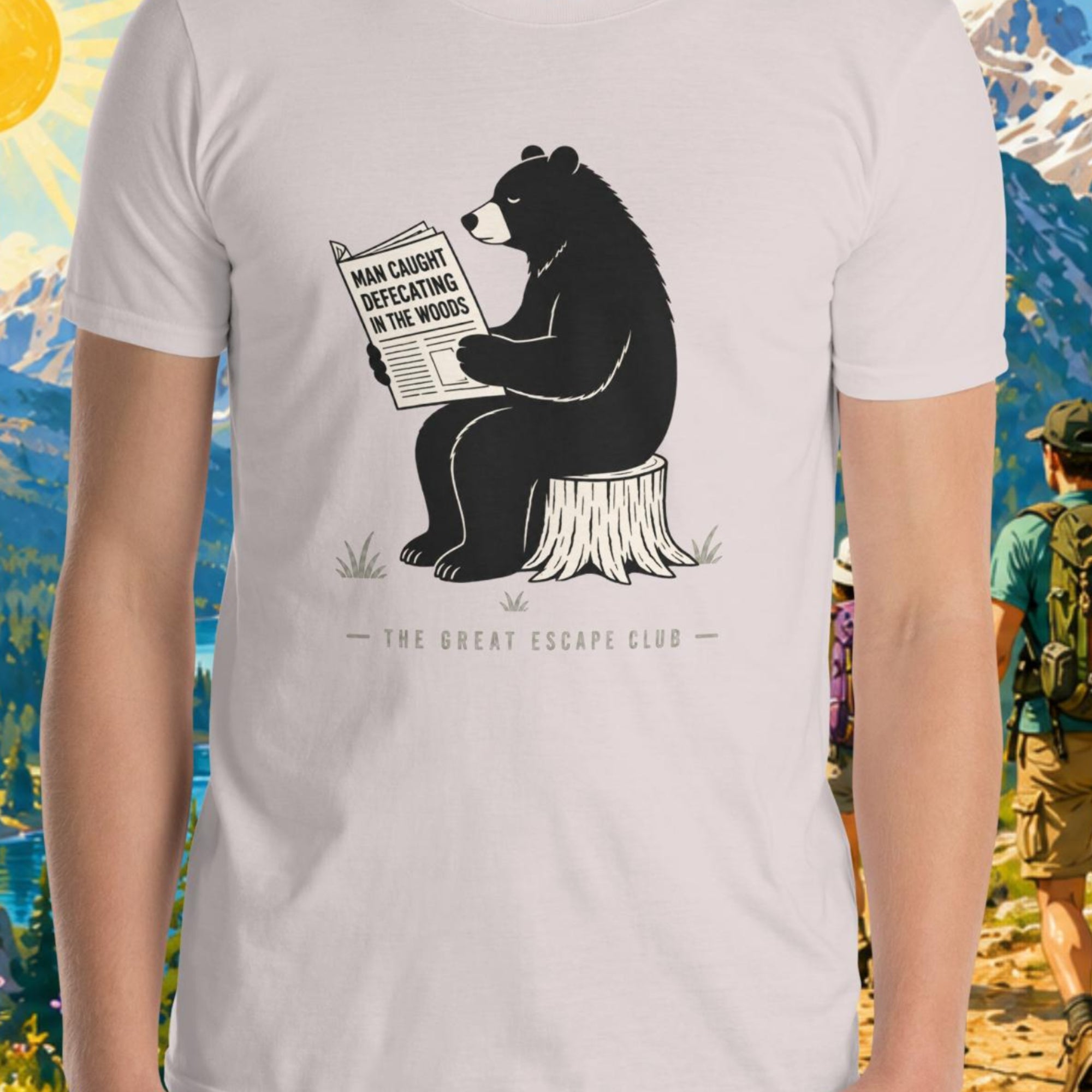 Person wearing a t-shirt with a bear graphic in front of a scenic mountain backdrop