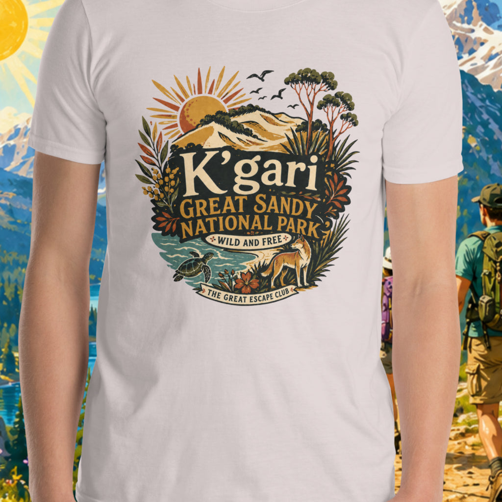 Person wearing a t-shirt with 'K'gari Great Sandy National Park' design, standing in front of a scenic mountain backdrop.
