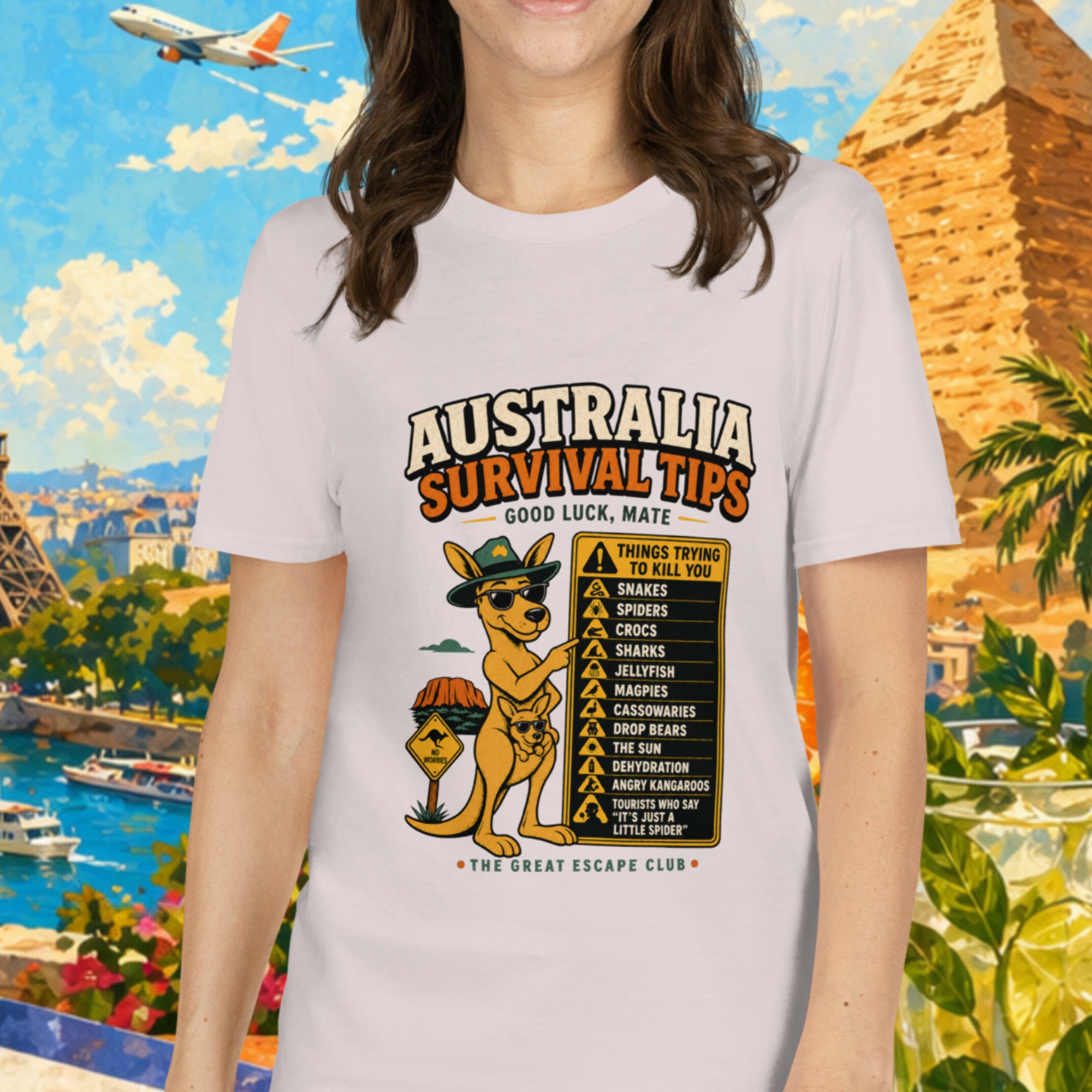 Woman wearing a t-shirt with 'Australia Survival Tips' design, standing in front of a colorful travel-themed background with Eiffel Tower and pyramids.