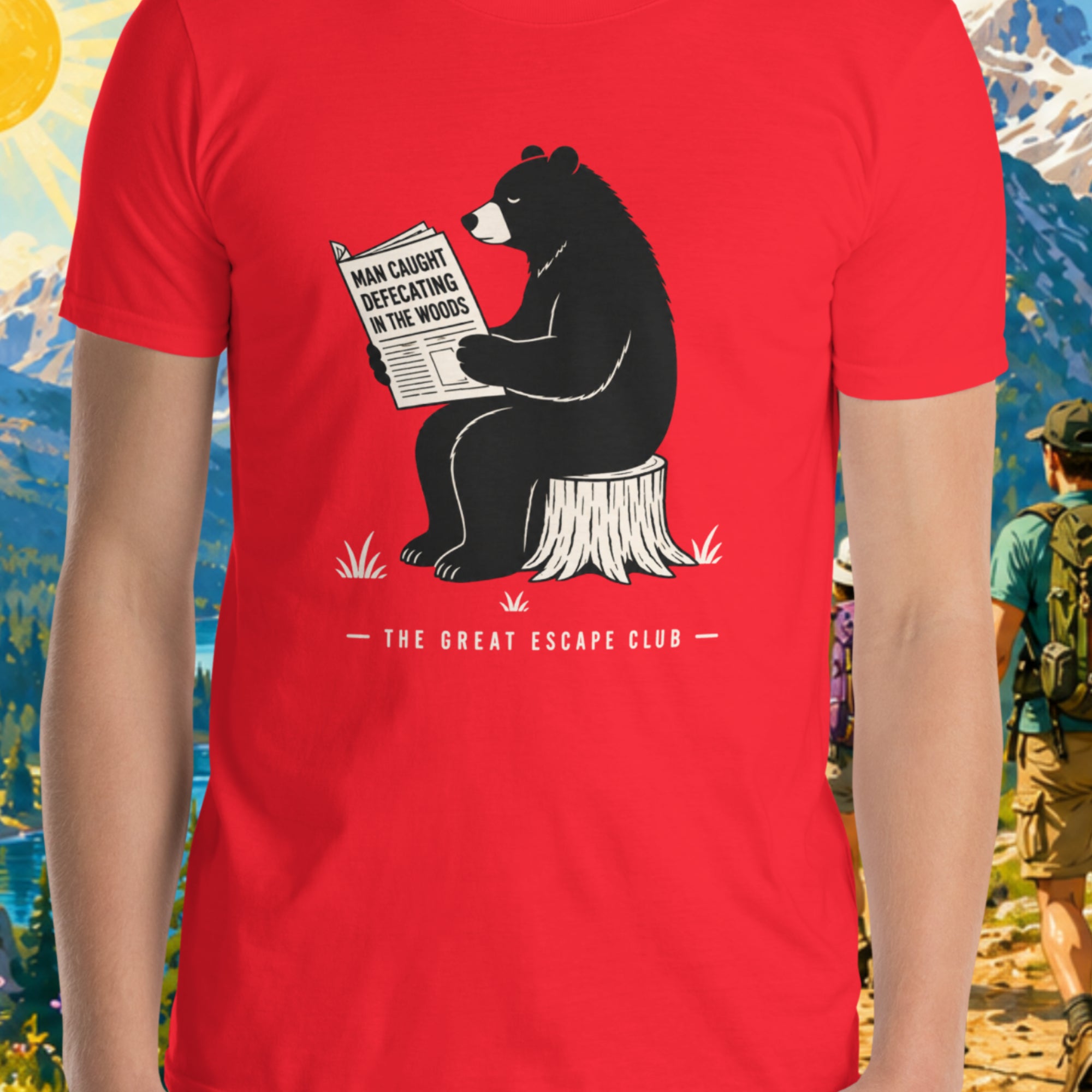 Person wearing a red t-shirt with a bear graphic in front of a scenic mountain backdrop