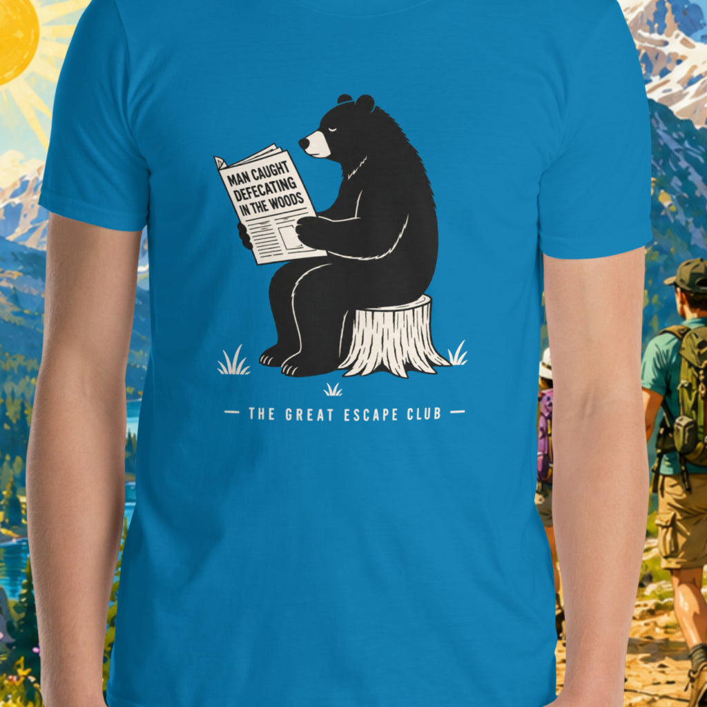 Blue t-shirt with bear reading newspaper graphic and 'The Great Escape Club' text, worn by a person in a forest setting.